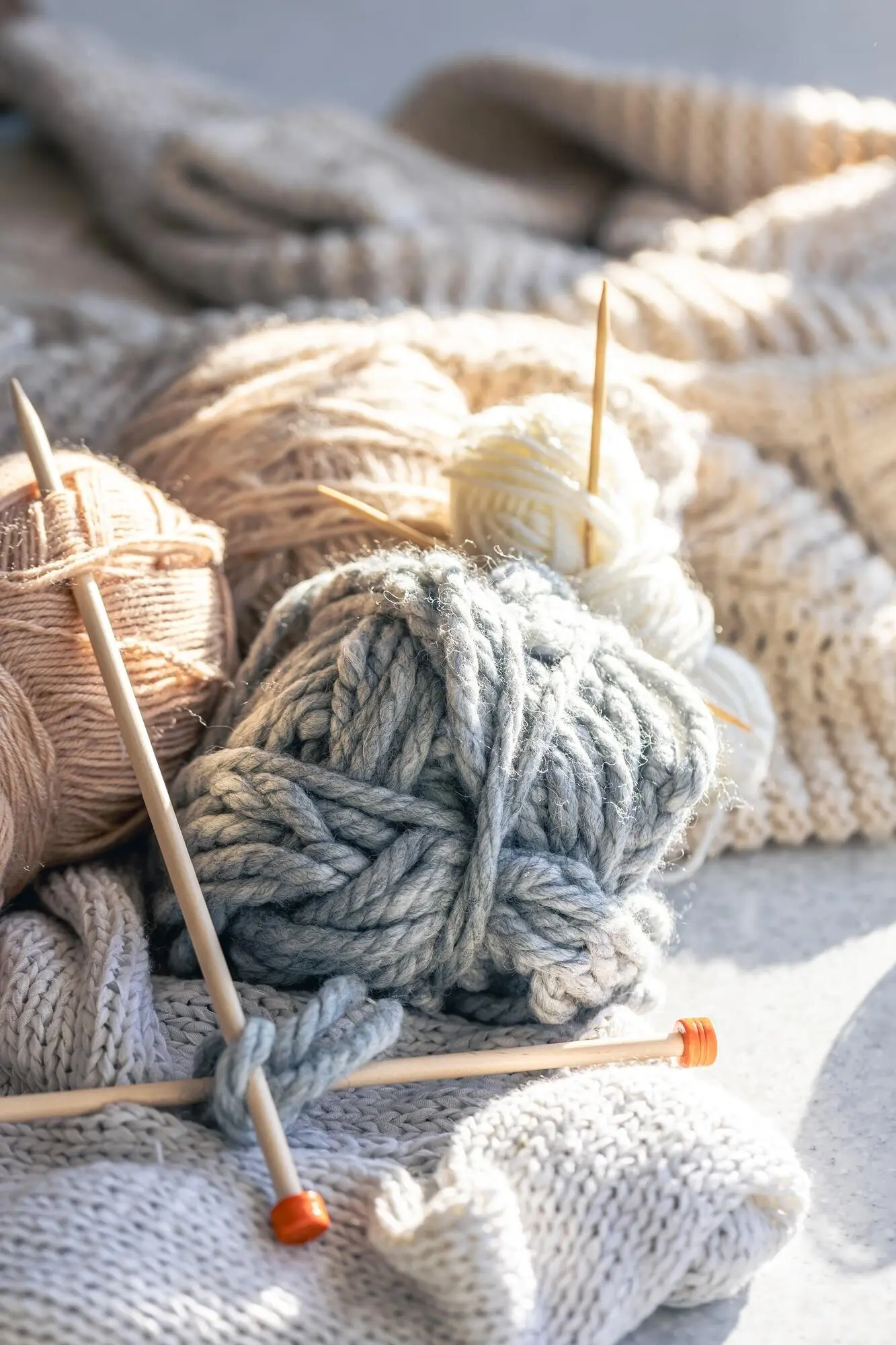 Nahaufnahme von pastellfarbenem Garn und Stricknadeln.